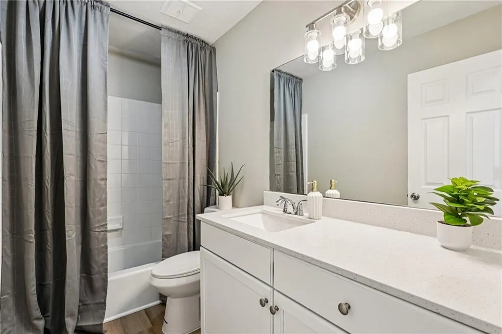Bathroom featuring shower / bath combination with curtain, vanity, dark wood-type flooring, and a chandelier