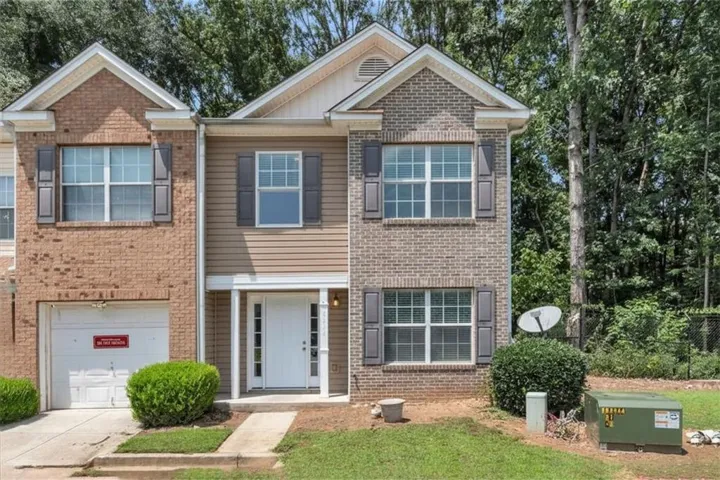Brick and siding exterior with decorative shutters, white entry door with sidelights, and an attached garage