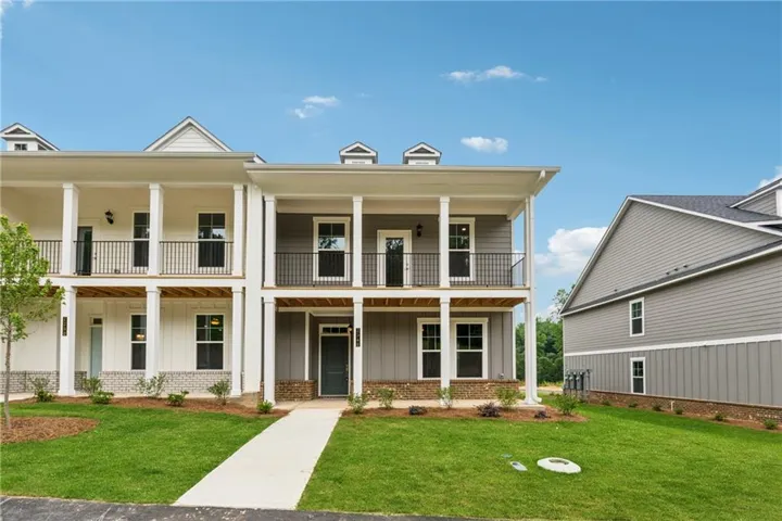 View of front of home featuring board and batten siding, covered porch, brick siding, and a front yard