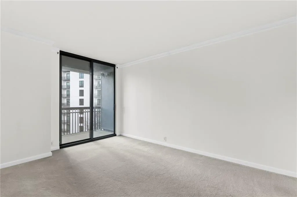 Unfurnished room featuring expansive windows, ornamental molding, and light carpet