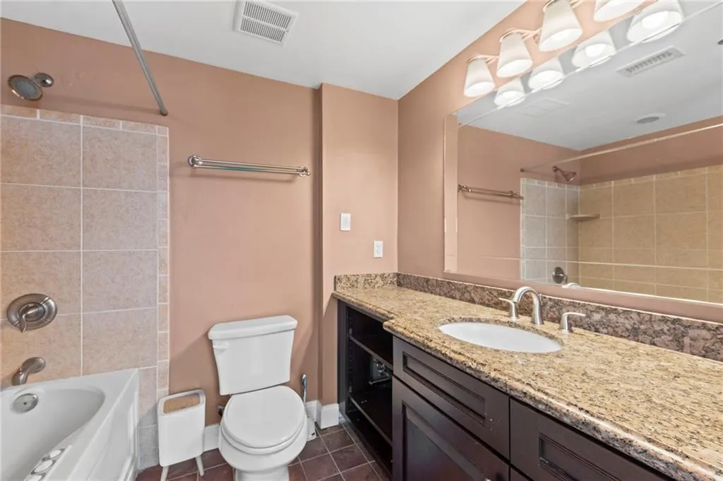 Full bathroom with  shower combination, vanity, and dark tile patterned flooring