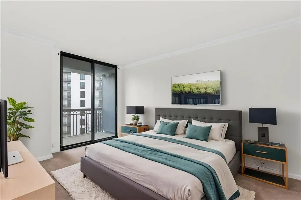 Bedroom featuring light carpet, expansive windows, ornamental molding, and access to exterior