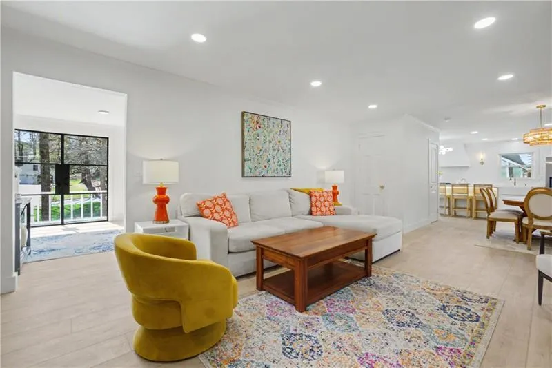 Living room featuring light wood-style floors, ornamental molding, and suspended lighting