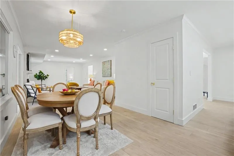 Dining room with light wood-type flooring, crown molding, and suspended lighting