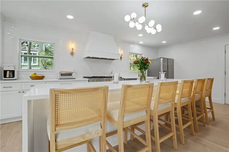 Kitchen with backsplash, light wood-style flooring, a breakfast bar, an island with sink, and ornamental molding