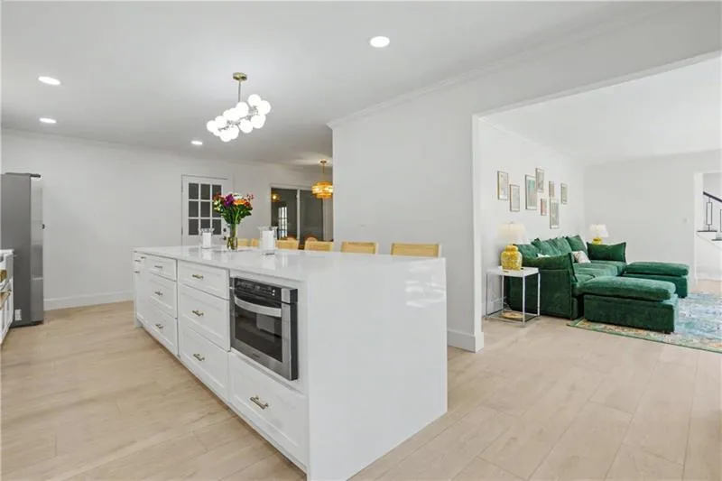 Kitchen with a kitchen island, light wood finished floors, stainless steel appliances, crown molding, and white cabinetry