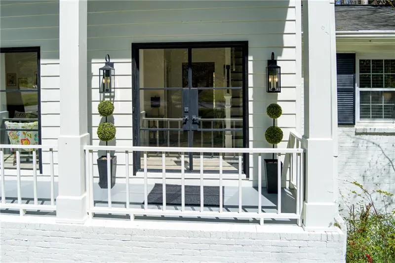 Doorway to property with covered porch, brick siding, and french doors
