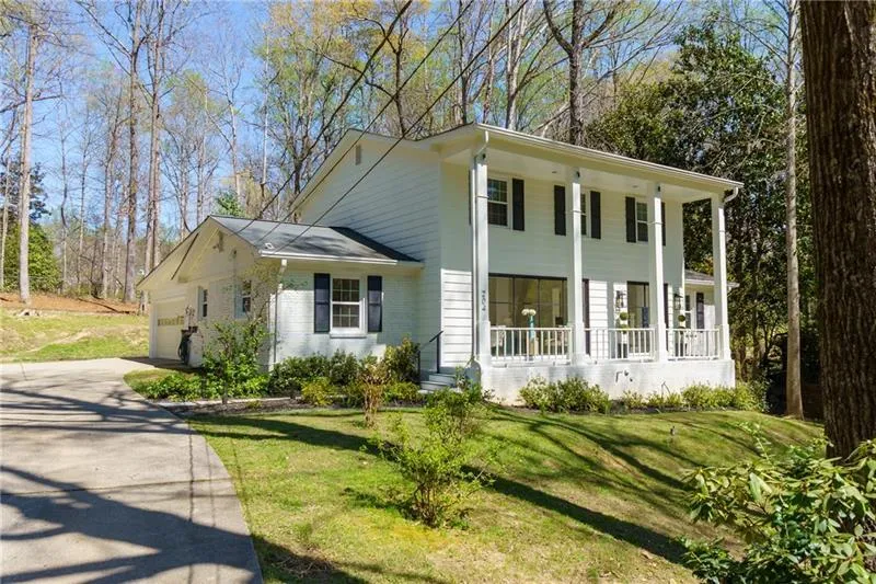 Neoclassical / greek revival house with a porch, a front yard, an attached garage, and driveway