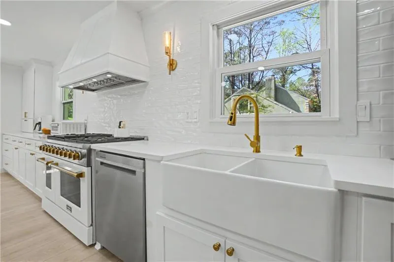 Kitchen with white cabinets, dishwasher, range with two ovens, light wood-style flooring, and tasteful backsplash