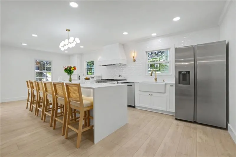 Kitchen with stainless steel appliances, a kitchen island, a kitchen breakfast bar, and white cabinets