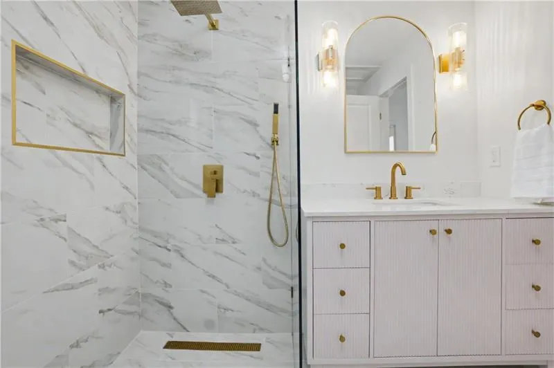 Full bath featuring vanity and a marble finish shower