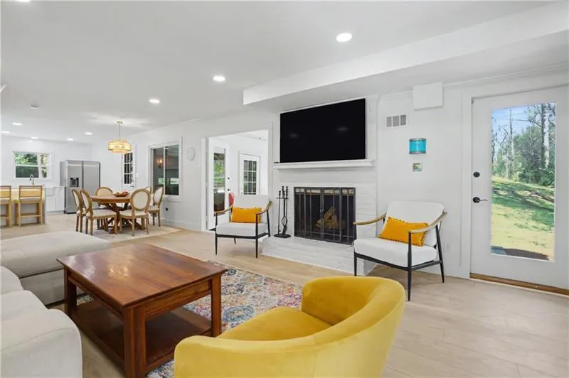 Living room with a fireplace, recessed lighting, light wood finished floors, and crown molding