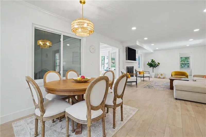 Dining area featuring light wood-style flooring, plenty of natural light, a fireplace, and a chandelier