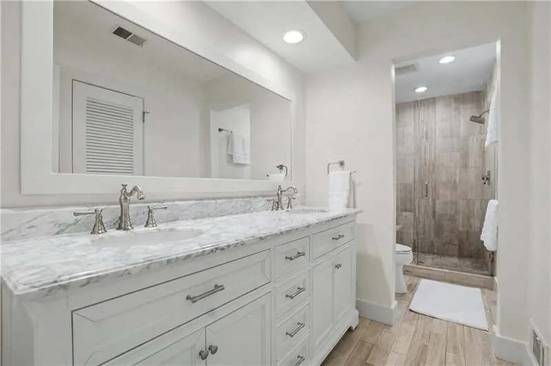 Full bath with double vanity, a stall shower, recessed lighting, and wood finish floors