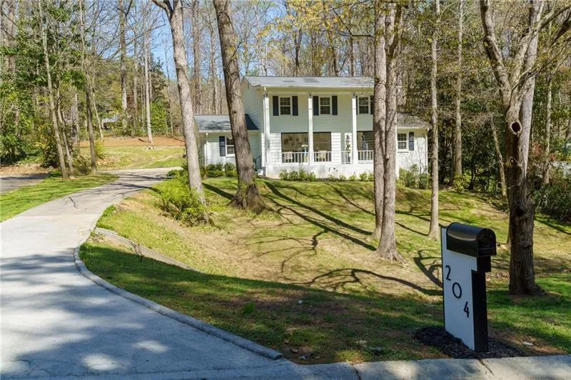 Greek revival house with a front lawn, covered porch, and driveway
