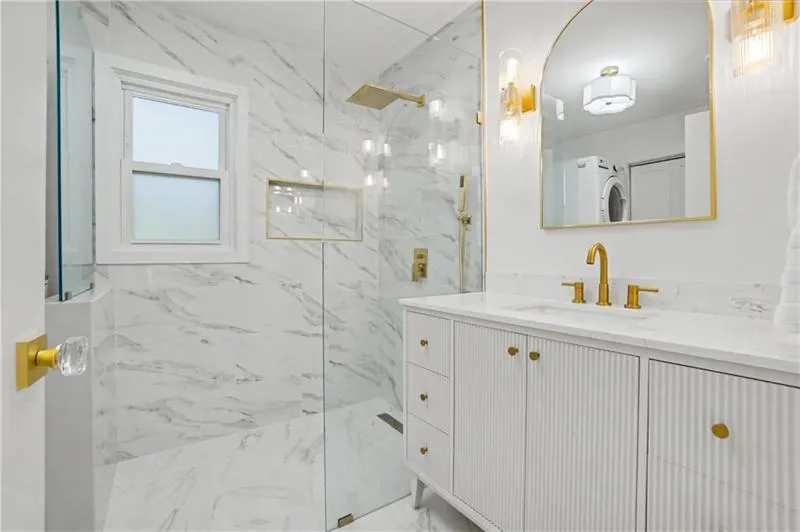 Bathroom featuring vanity, a marble finish shower, and washer / clothes dryer