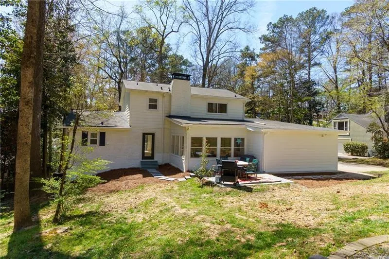 Rear view of property featuring a patio, a lawn, brick siding, a chimney, and entry steps