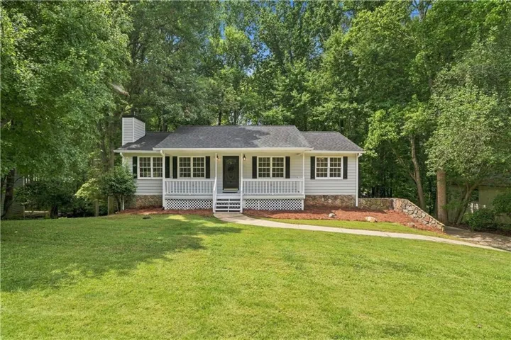 Ranch-style residence featuring light gray siding, a covered front porch with white railings, and a dark asphalt shingle roof