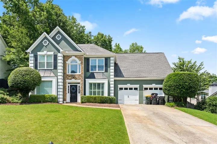 View of front of home with stone siding, stucco siding, driveway, a front yard, and roof with shingles