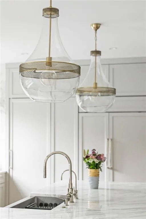 Recessed lighting and two pendant fixtures illuminate the stone countertop with an integrated sink and gooseneck faucet
