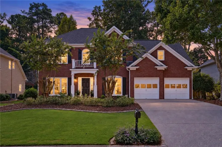 Brick exterior with white trim, a covered entry, and a second-story balcony
