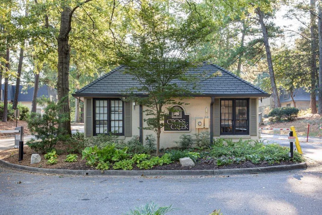 Bungalow-style home featuring a high end roof, stucco siding, and view of wooded area