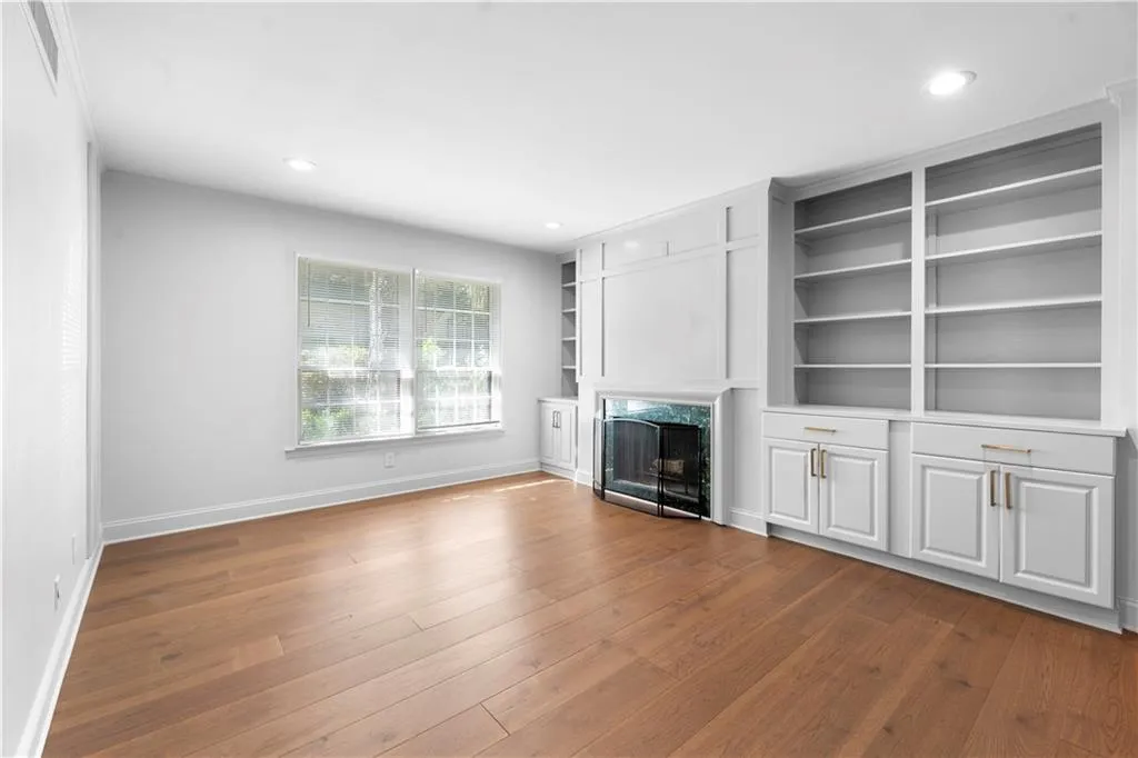 Unfurnished living room featuring built in features, dark wood-style flooring, a premium fireplace, and recessed lighting