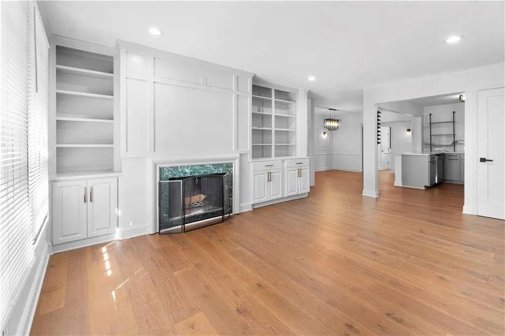 Unfurnished living room with built in shelves, light wood-style floors, a high end fireplace, and recessed lighting