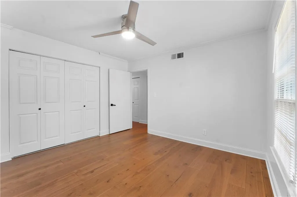 Unfurnished bedroom featuring wood finished floors, a ceiling fan, a closet, and ornamental molding