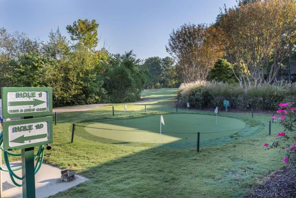 View of home's community with a putting area, a lawn, and view of scattered trees