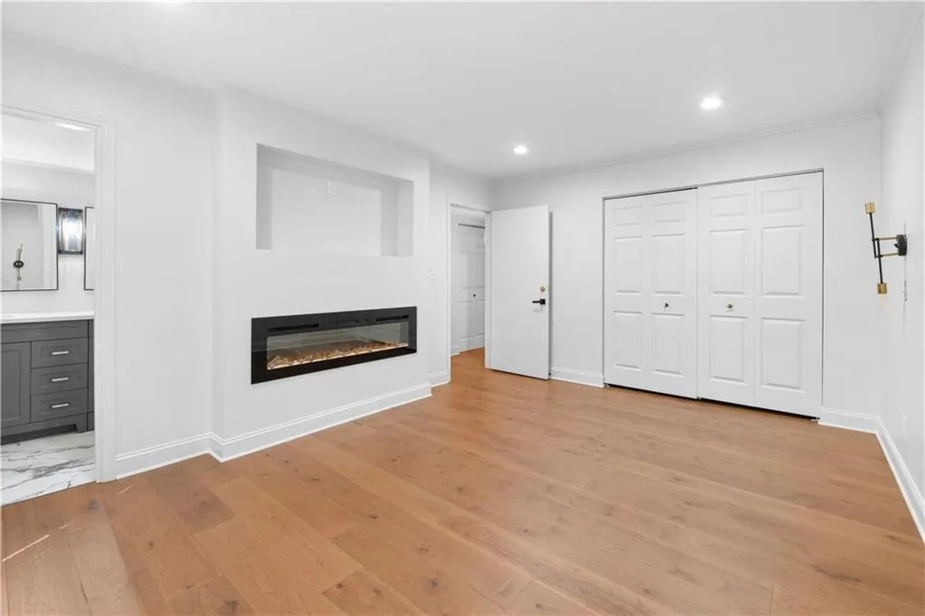 Unfurnished living room featuring a glass covered fireplace, recessed lighting, light wood-style floors, and ornamental molding