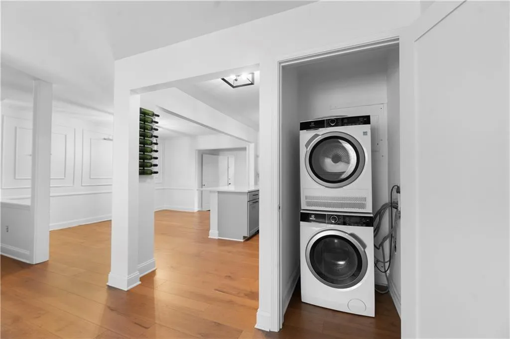 Laundry room featuring light wood-style flooring and stacked washer / dryer