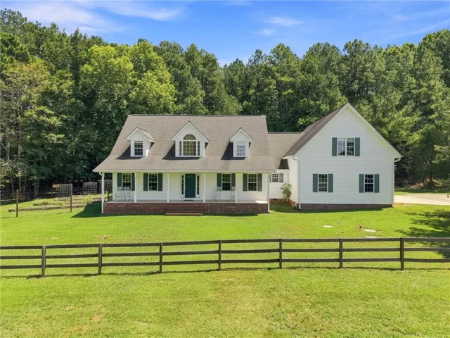 White siding exterior with a dark shingle roof, green shutters, and a covered front porch