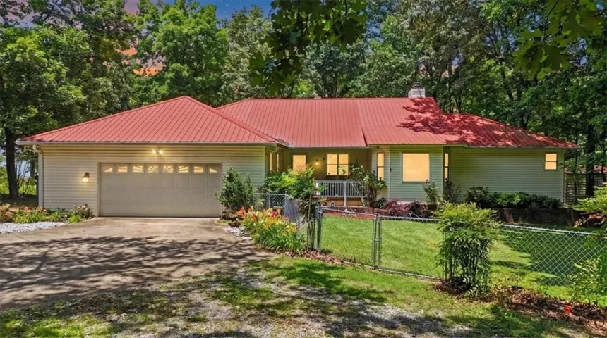 Siding exterior with a red metal roof, attached garage, and front porch