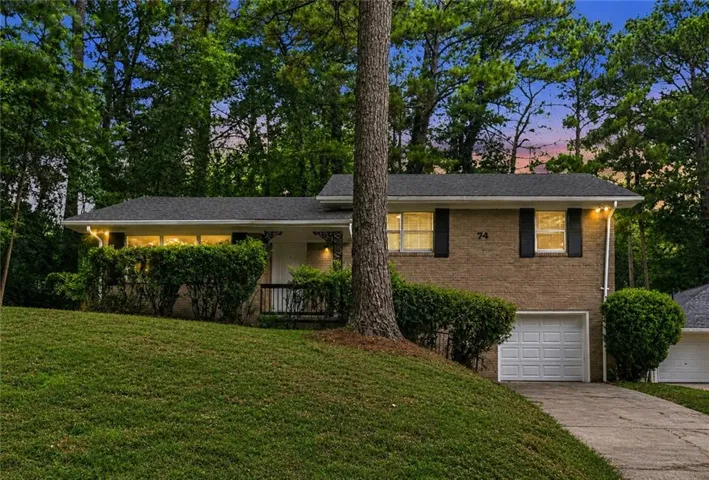 Brick exterior residence with a sloped front lawn and mature tree