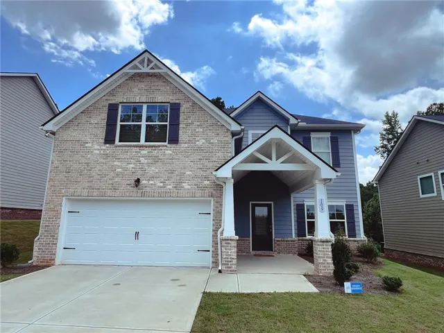 Brick and siding exterior with a covered entry, attached two-car garage, and established landscaping