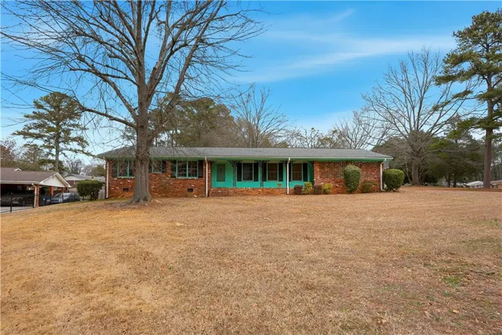Ranch-style home with brick siding, a front yard, and covered porch