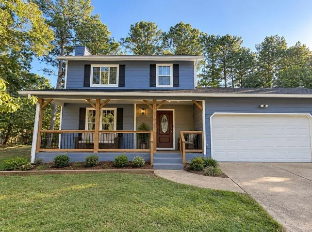 Two-story exterior with blue siding, a covered porch with wood accents, an integrated garage, and a concrete driveway