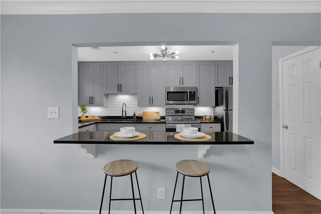 Kitchen with a notable chandelier, gray cabinetry, backsplash, and stainless steel appliances