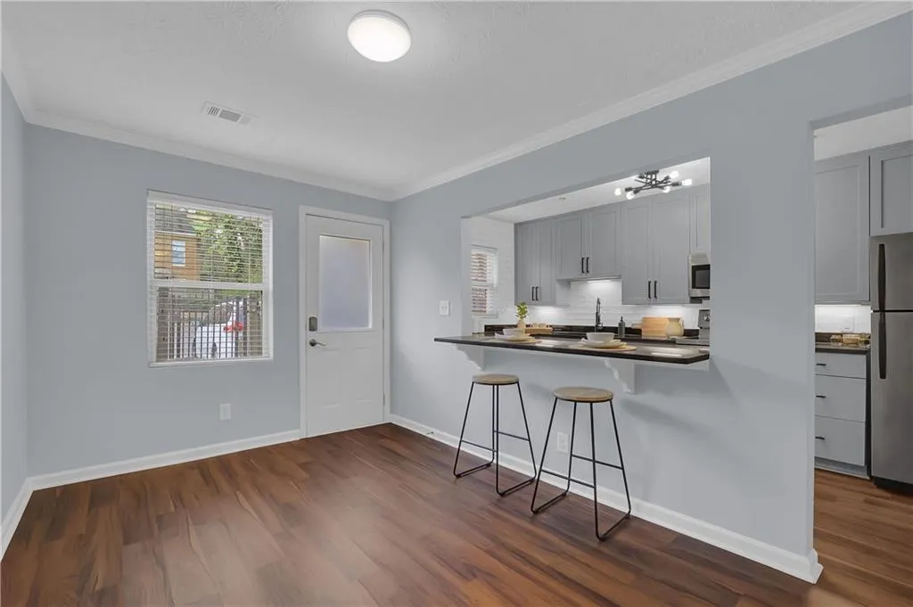 Kitchen with dark hardwood / wood-style flooring, a kitchen bar, stainless steel refrigerator, and crown molding