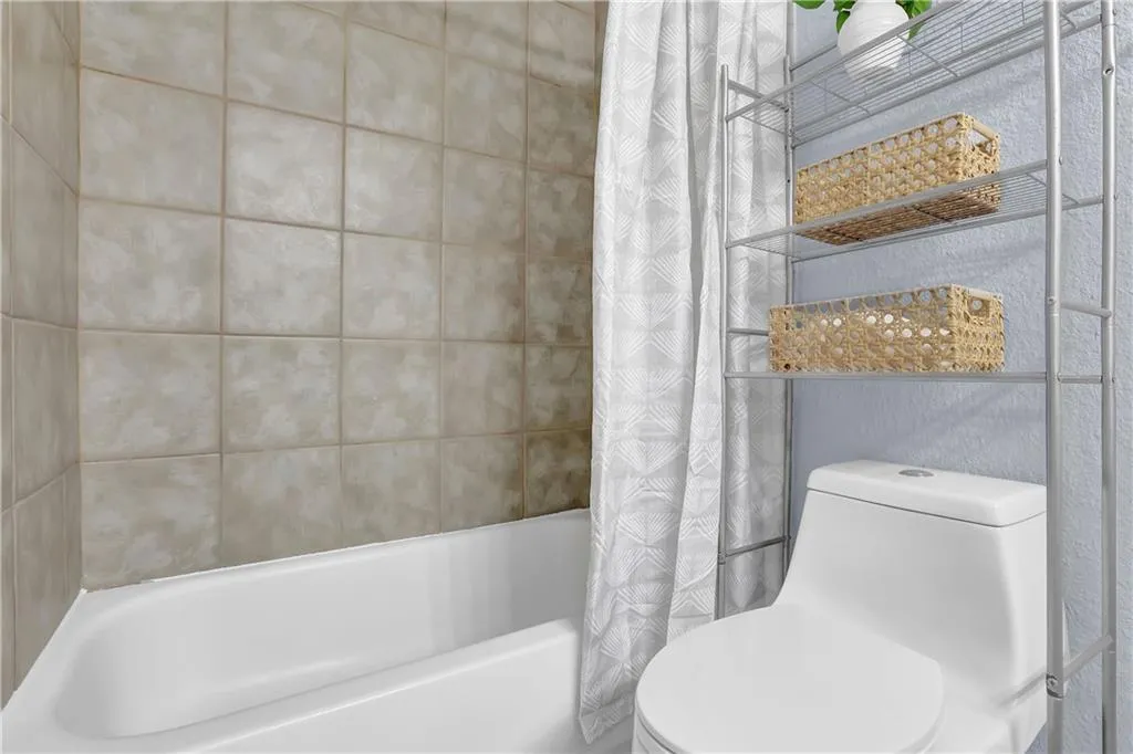 Bathroom with toilet and shower / tub combo with curtain