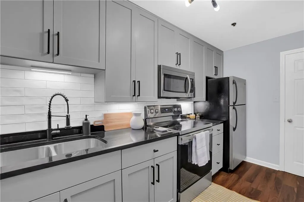 Kitchen with sink, tasteful backsplash, dark hardwood / wood-style floors, appliances with stainless steel finishes, and gray cabinets