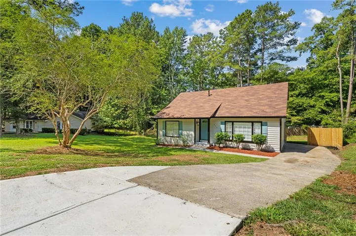Siding exterior with a shingle roof, established landscaping, and a partial wood privacy fence
