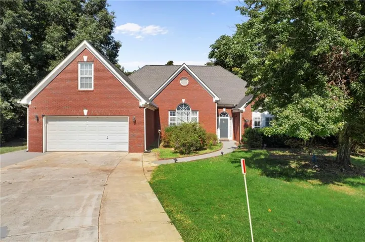 Red brick exterior with white trim, a two-car garage, and a curved paved walkway