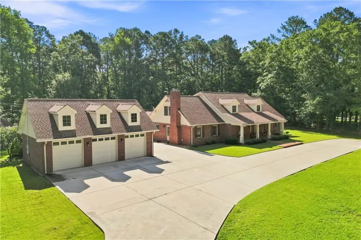 Brick exterior residence with a columned front porch, multi-car garage, and a concrete driveway