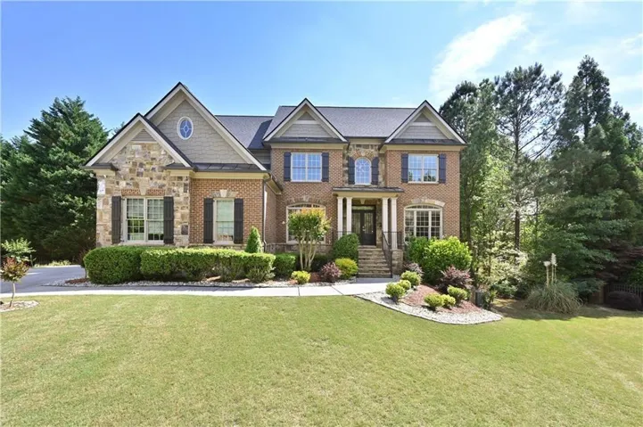 Traditional two-story home featuring a brick and stone facade with dark shutters