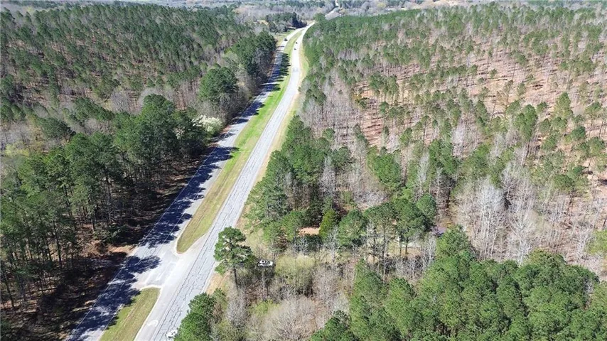 Bird's eye view of the property. There is a small outparcel where the white car can be seen through the trees.  It is an old, abandoned church. Property is on both sides of this highway.