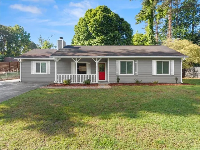 Ranch-style exterior with gray siding, white window trim, and a bright red entry door