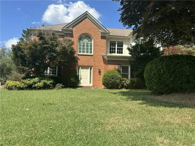 Brick and siding exterior with a prominent arched window, white-framed double-hung windows, and a light-colored entry door