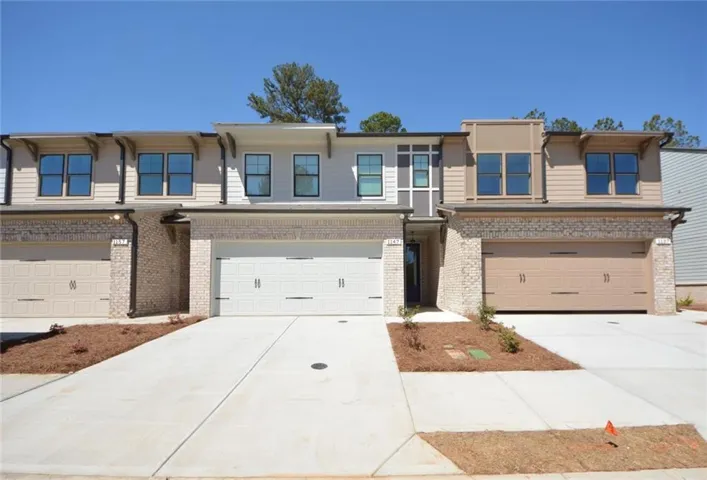 Contemporary townhome exterior featuring light-colored brick and horizontal siding